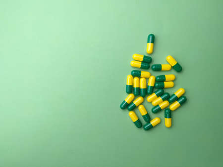 Some colored medicine pills are on a green background with copy and text space.Medical concept.の写真素材