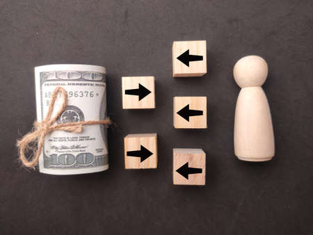 Banknotes and pegdoll with arrows one in a different direction and another .Different thinking, individuality.の写真素材