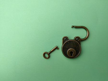 Vintage bronze key and padlock on soft green paper, background image with copy and text space.