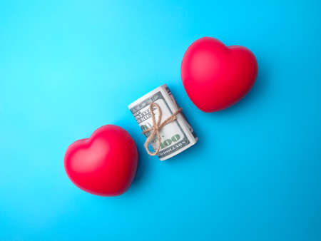 Close-up top view banknotes and two red heart shape on blue background. Money and love concept.の写真素材