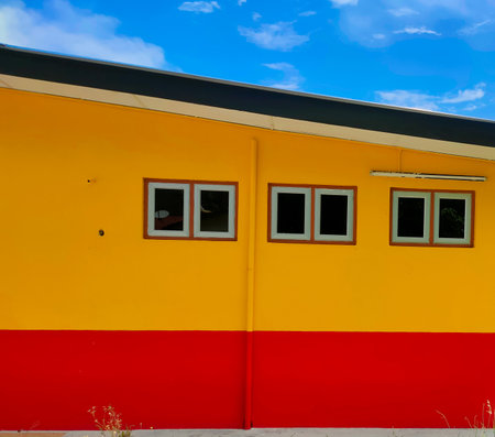 A house painted red and yellow against a background of blue clouds.の写真素材