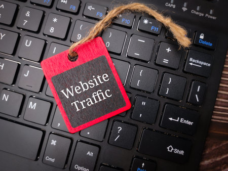 Wireless keyboard  with the word Website Traffic on wooden background.