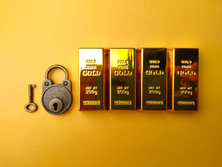 Vintage padlock with gold bar on a yellow background.の写真素材