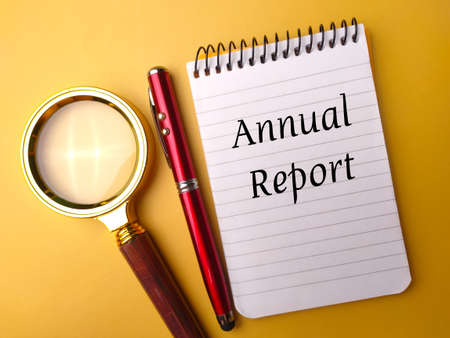 Magnifying glass and pen with the word Annual Report on yellow background.の写真素材