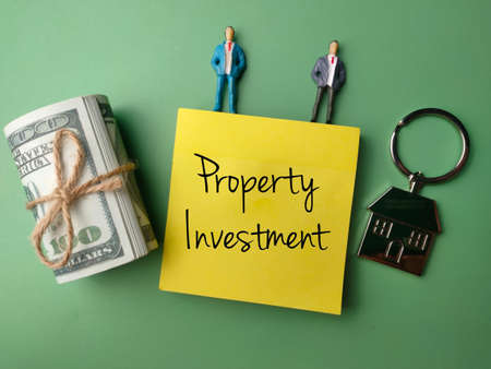 Banknotes,miniature people and house keychain with the word Property Investment.の写真素材