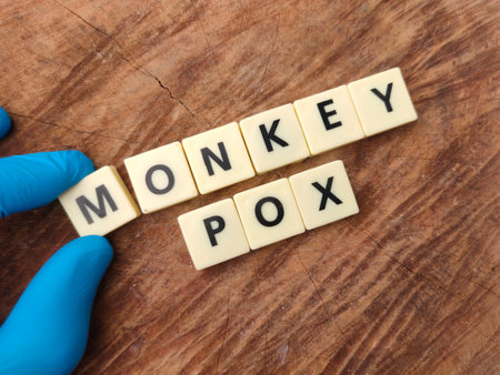 Hand holding toys word with the word MONKEY POX on wooden background.の写真素材