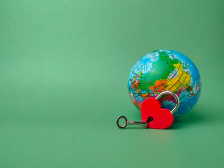 Heart shaped red lock with key and earth globe on a green background. Concept of love nature forever with padlock.の写真素材