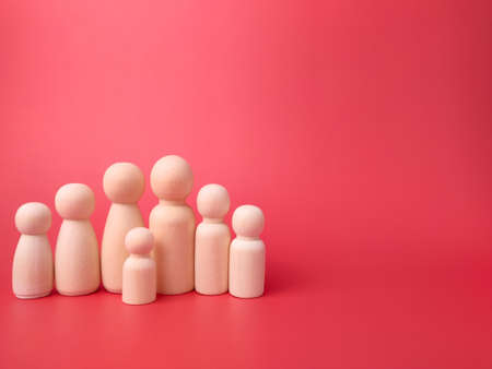 Wooden figures on a red background with copy space. Concept of family.の写真素材