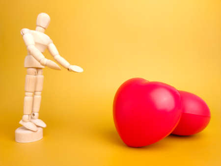 Wooden mannequin and red love shape on a yellow background.の写真素材