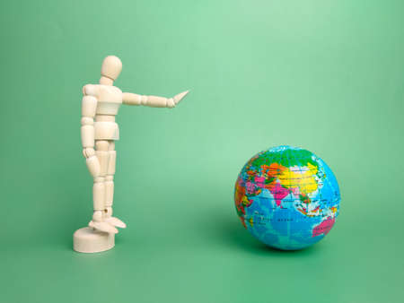Wooden mannequin and earth globe on a green backgroundの写真素材