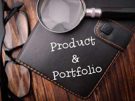 Top view magnifying glass,glasses and notwbook with the word Product and Portfolio.の写真素材