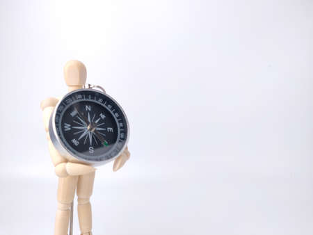 Wooden mannequin holding compass on a white background with copy space.の写真素材