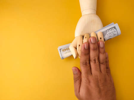Someone's hand was pushing the wooden hand that was holding the banknote in his hand.の写真素材