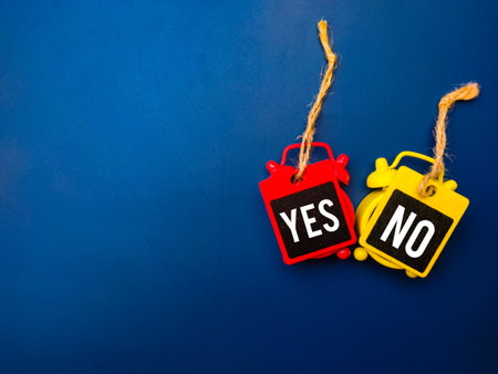 Top view clock and colored wooden board with the word YES NO on blue background. Business concept.の写真素材