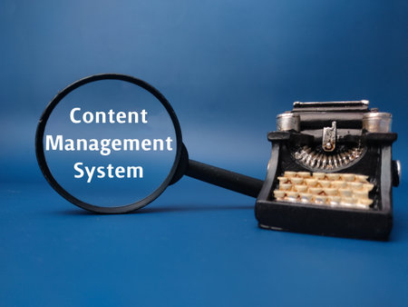 Magnifying glass and vintage type writter with the word Content Management System on blue background.の写真素材