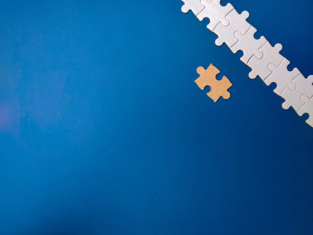Unfinished white jigsaw puzzle pieces on blue background