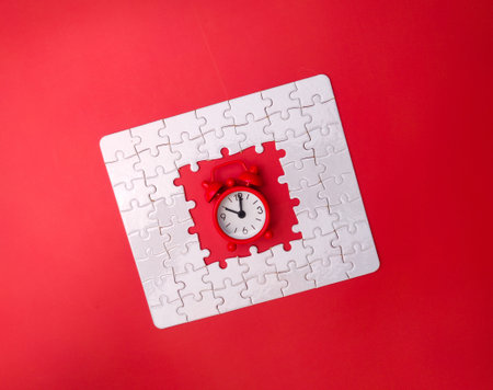 Concept red alarm clock and puzzle on red background