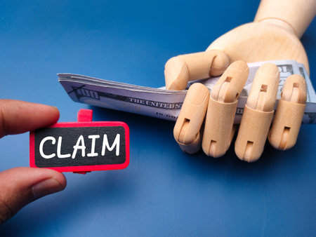 Wooden board with the word CLAIM and wooden hand holding banknotes. Business concept.