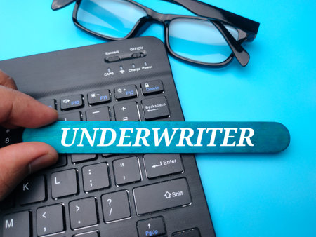 Keyboard and glasses with the word UNDERWRITER on a blue background.の写真素材