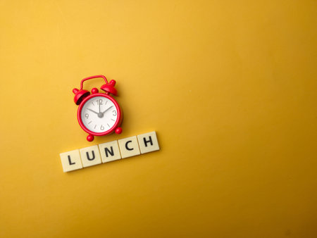 Red alarm clock with word LUNCH on a yellow background.