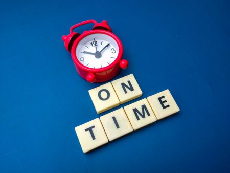 Red alarm clock with the  ON TIME on a blue background.の写真素材
