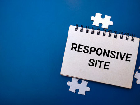 Notebook and white puzzle with the word RESPONSIVE SITE on blue background. Business concept.の写真素材