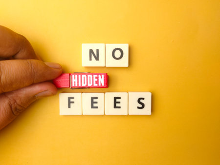 Hand holding wooden clips with the word NO HIDDEN FEES on yellow background.の写真素材