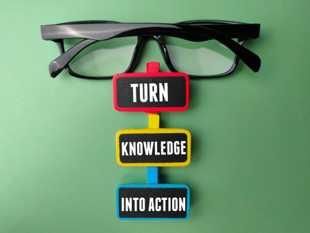 Glasses and colored wooden board with the word TURN KNOWLEDGE INTO ACTION. Business concept.の写真素材