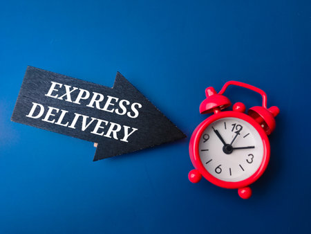 Red alarm clock and wooden arrow with word EXPRESS DELIVERY on blue background. Business concept.の写真素材