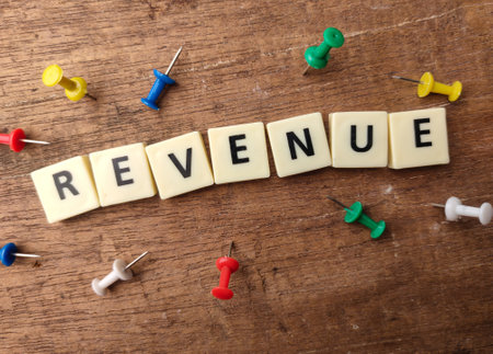 Toys word and pins board with the word REVENUE on wooden background.Business concept.の写真素材