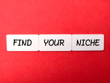 Wooden board with text FIND YOUR NICHE on a red background.Business concept.の写真素材