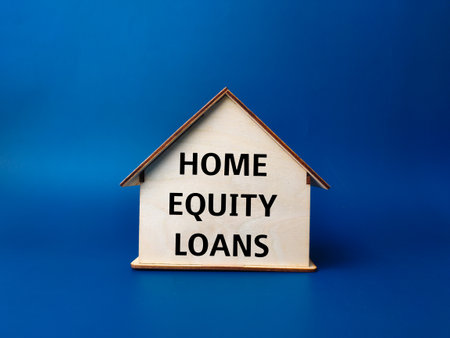 Wooden house with text HOME EQUITY LOANS on blue background.の写真素材