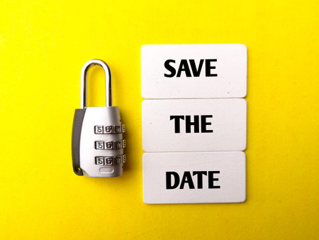 Padlock and wooden board with the word SAVE THE DATE on a yellow background. Business concept.
