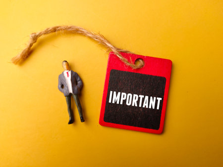 Wooden board and miniature people with the word IMPORTANT on yellow backgroundの写真素材