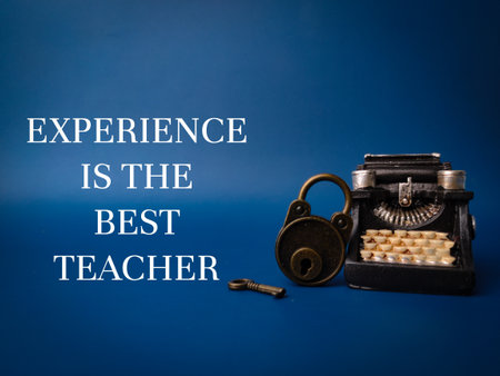 Vintage typewritter and padlock with the word EXPERIENCE IS THE BEST TEACHER on blue backgroundの写真素材