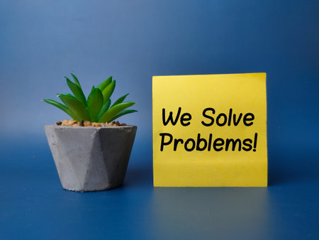 Green plan and sticky note with the word We Solve Problems on blue backgroundの写真素材