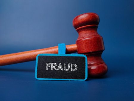 Gavel and wooden board with the word FRAUD on a blue background.の写真素材