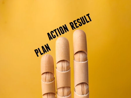Wooden hand with the word PLAN ACTION RESULT on a yellow background