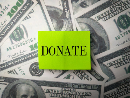 Sticky note with word DONATE on a banknotes backgroundの写真素材