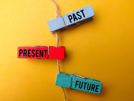 Colored wooden clips and roots with the word PAST PRESENT FUTURE on yellow backgroundの写真素材