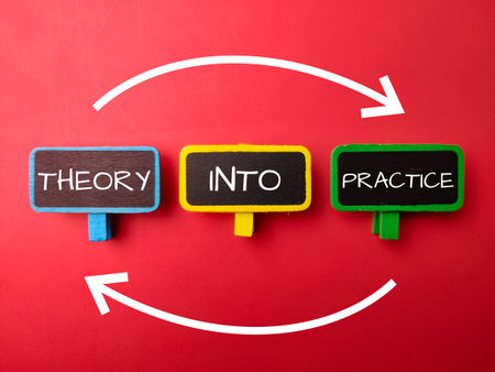 Wooden board with the word THEORY INTO PRACTICE on a red backgroundの写真素材