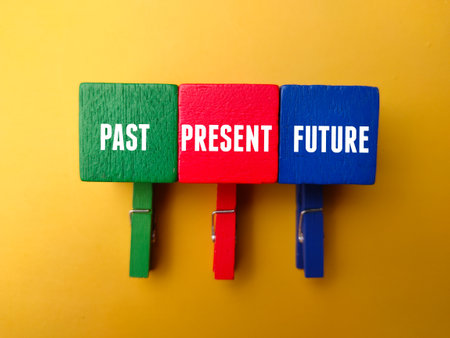 Colored wooden clips and wooden cube with the word PAST PRESENT FUTURE on yellow backgroundの写真素材