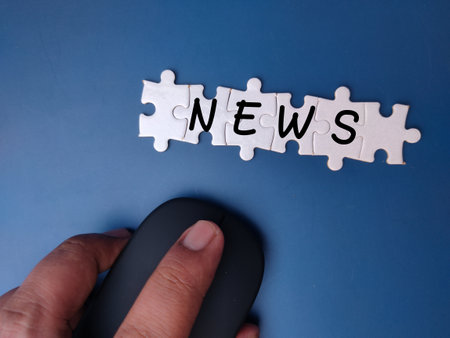 Wireless mouse and white puzzle with the word NEWS on a blue backgroundの写真素材