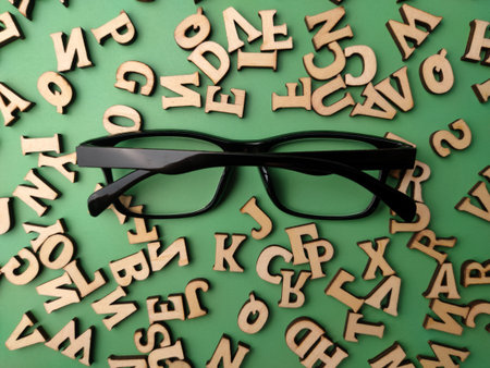Top view black glasses and wooden word on a green background
