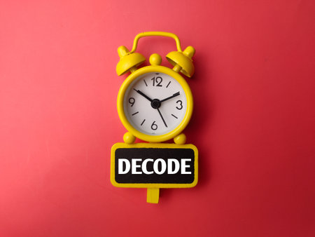 Yellow alarm clock and wooden board with word DECODE on a red background
