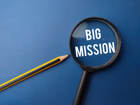 Magnifying glass and pencil with the BIG MISSION on a blue backgroundの写真素材