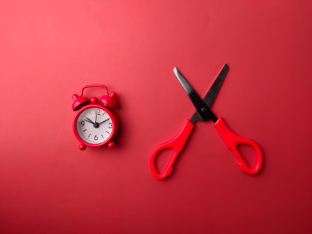 Top view red scissors with red alarm clock on a red backgroundの写真素材