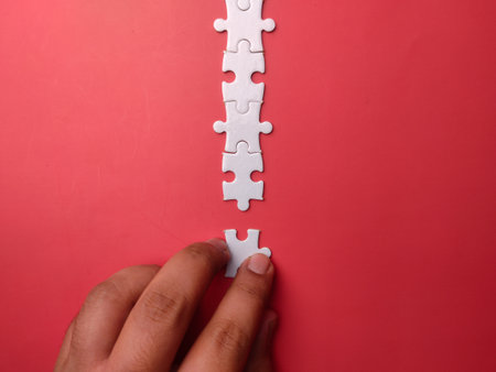 Top view someone hand holding white puzzle on a red background with copy spaceの写真素材