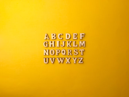 Set of 26 wooden letters,whole alphabet on yellow background, view from above.の写真素材