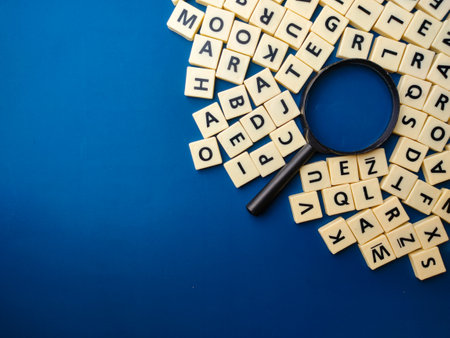 Top view magnifying glass and toys letters on a blue background with copy space.の写真素材